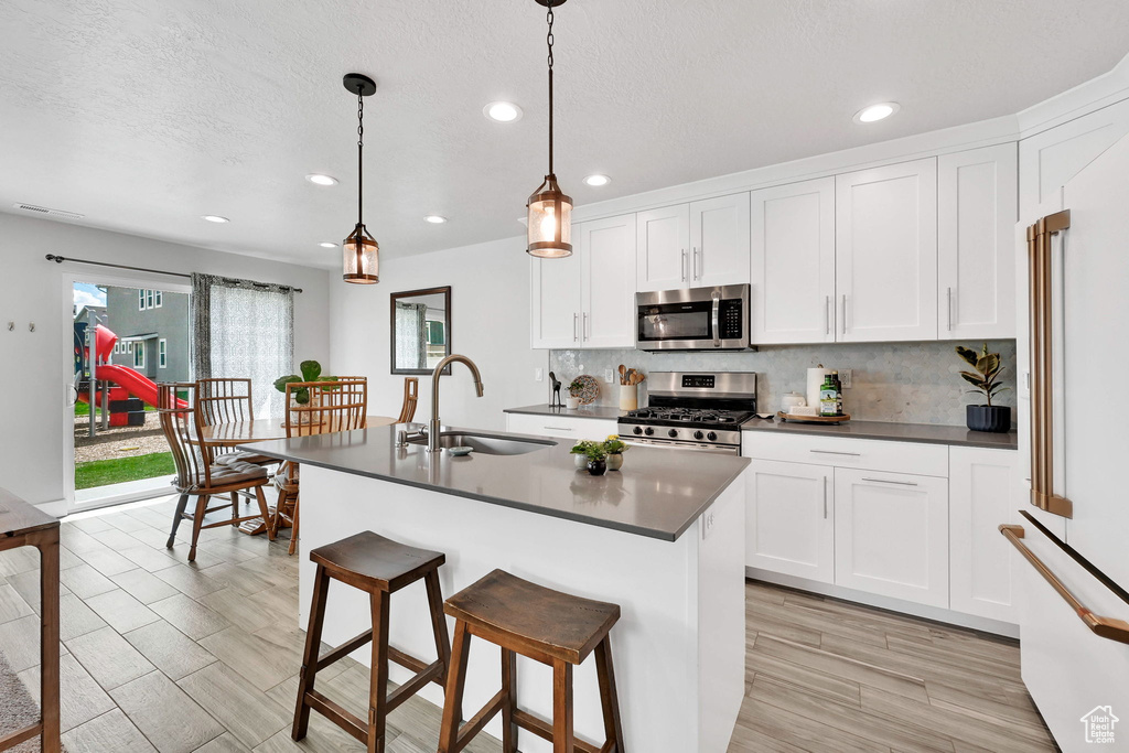 Kitchen featuring decorative backsplash, dark countertops, recessed lighting, a sink, and appliances with stainless steel finishes