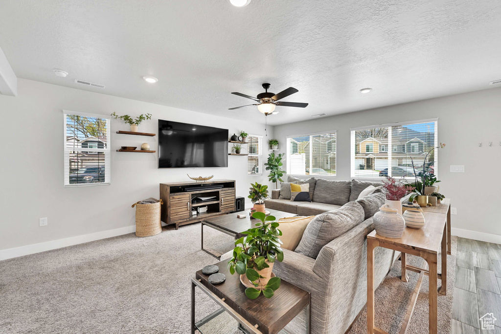 Living area with ceiling fan, baseboards, visible vents, and a wealth of natural light