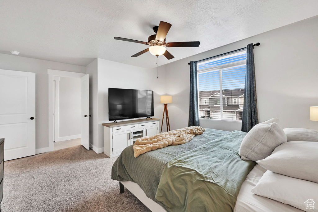 Carpeted bedroom featuring baseboards, a ceiling fan, and a textured ceiling