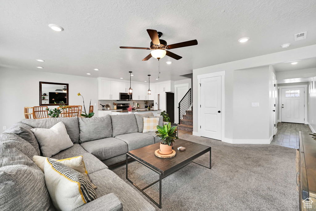 Living area with recessed lighting, ceiling fan, visible vents, and stairway