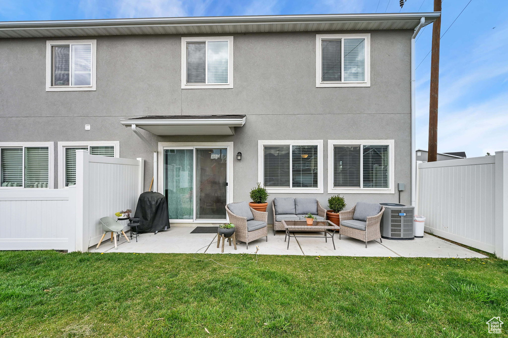 Back of property featuring fence, outdoor lounge area, cooling unit, a lawn, and a patio