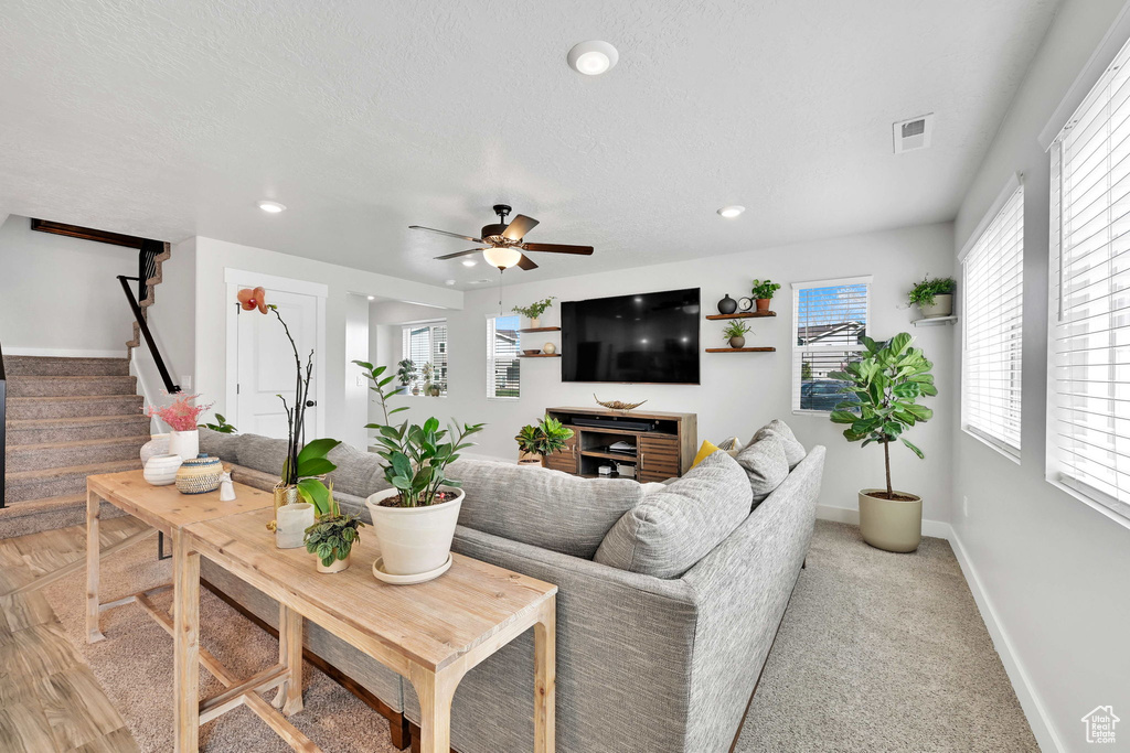 Living room featuring visible vents, baseboards, a wealth of natural light, and stairway
