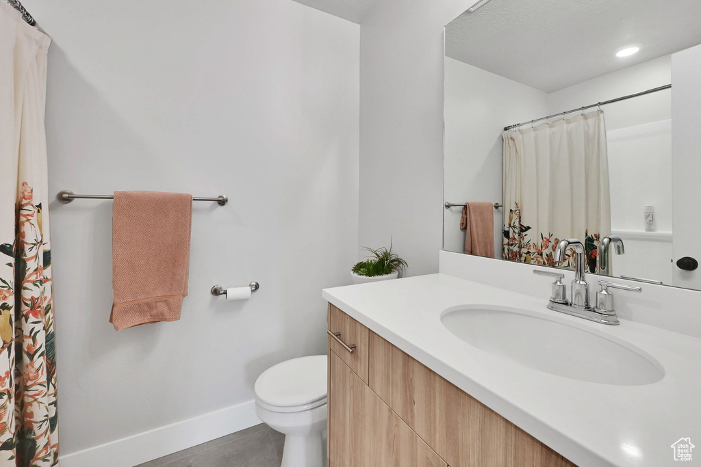 Full bath with baseboards, tile patterned floors, toilet, and vanity