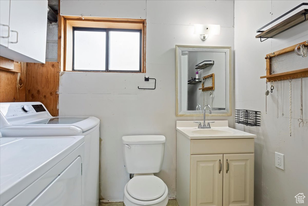 Bathroom featuring toilet, washer and clothes dryer, and vanity