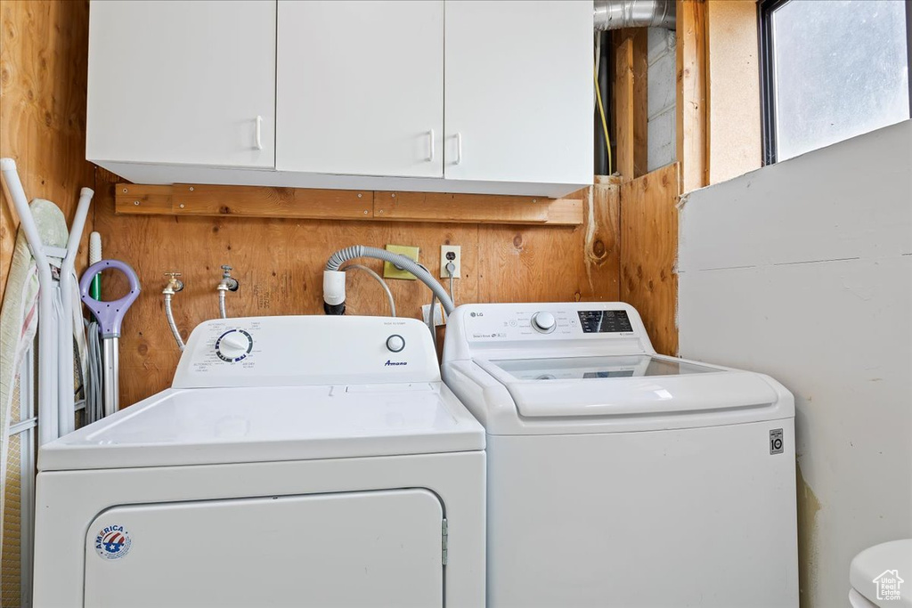Clothes washing area with laundry area, wooden walls, and washer and dryer
