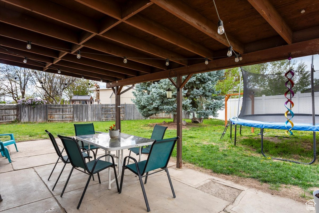 View of patio / terrace with a fenced backyard, outdoor dining space, and a trampoline