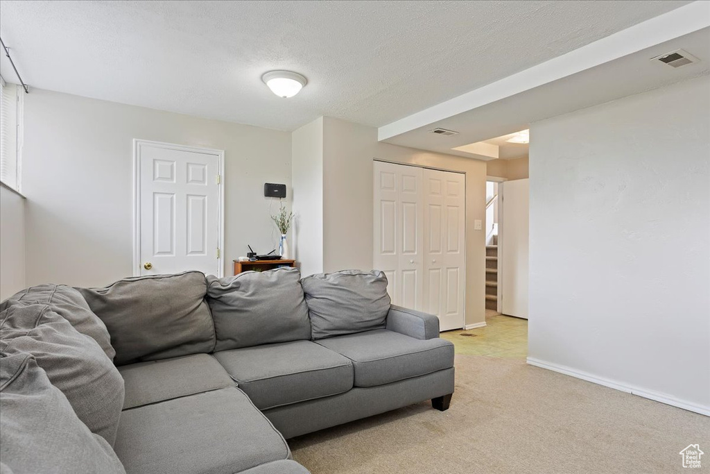 Living room featuring visible vents, baseboards, light colored carpet, and stairway