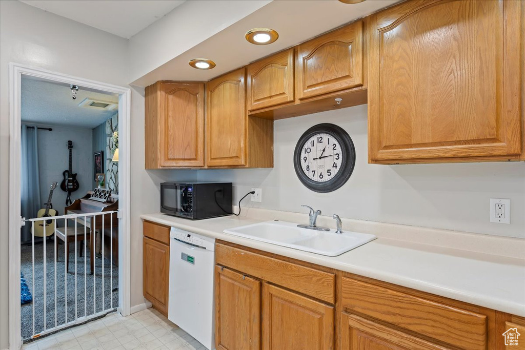 Kitchen featuring visible vents, black microwave, light countertops, a sink, and dishwasher