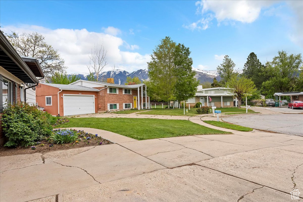 View of front of property featuring brick siding, a garage, a mountain view, and a front lawn