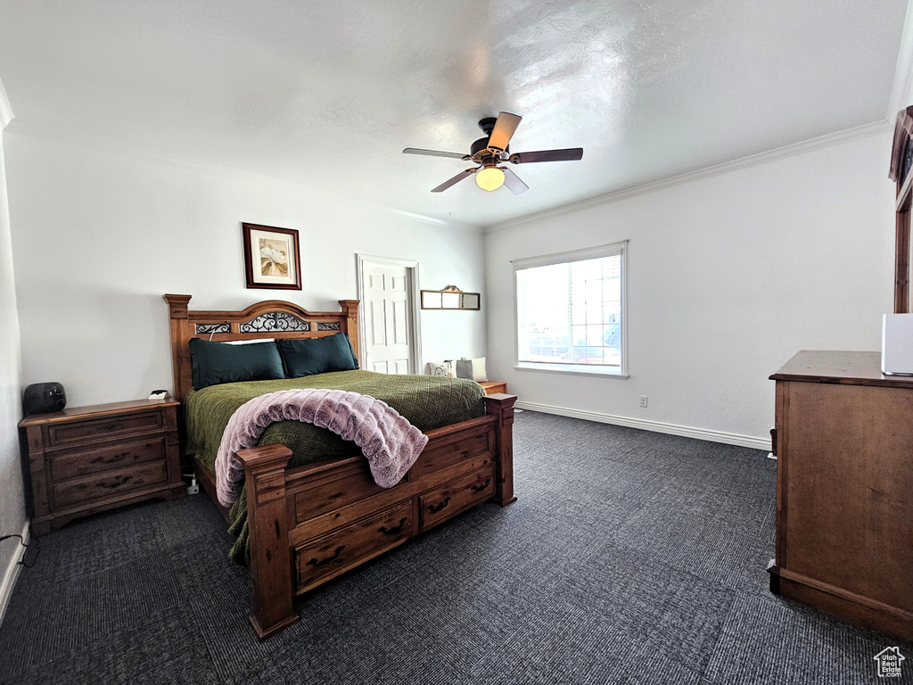 Bedroom with baseboards, ornamental molding, a ceiling fan, and dark colored carpet