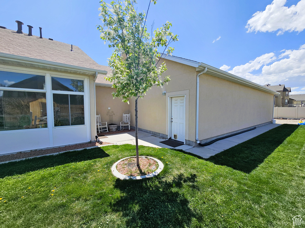 Back of house featuring a patio, stucco siding, and a yard