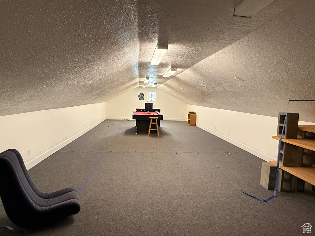 Bonus room featuring a textured ceiling, baseboards, lofted ceiling, and carpet