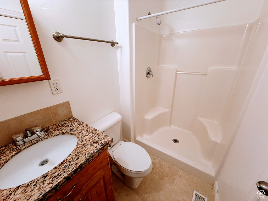Bathroom featuring a shower, toilet, vanity, and tile patterned floors