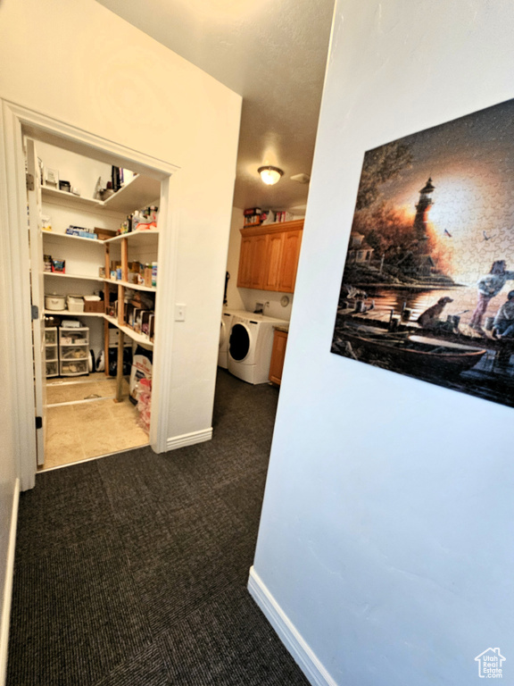 Hall featuring washer / dryer, baseboards, and dark carpet