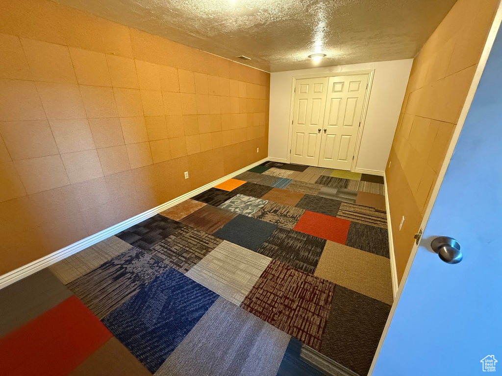 Carpeted spare room featuring a textured ceiling and baseboards
