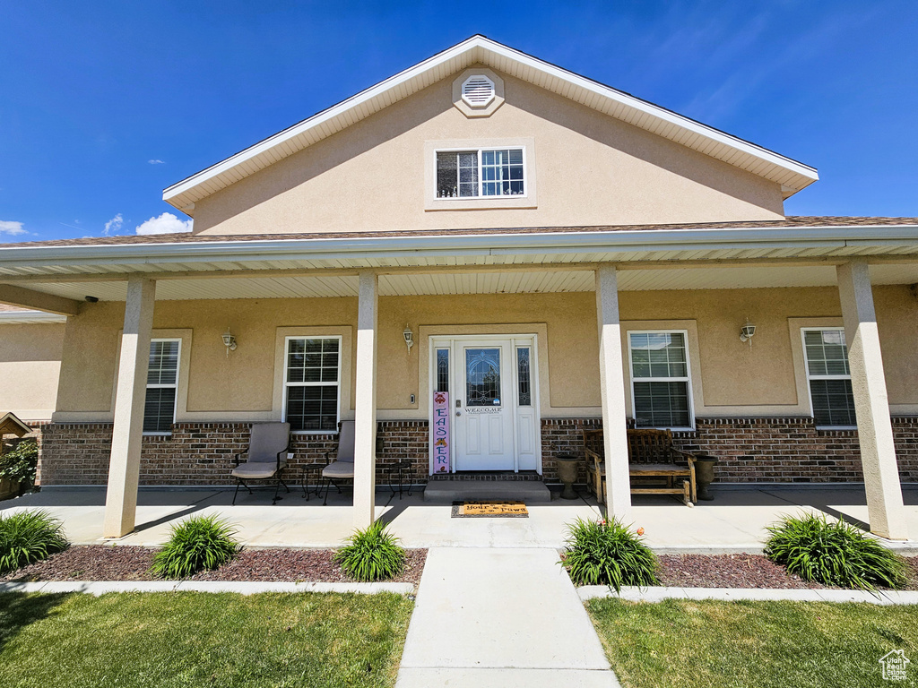 Property entrance with covered porch, stucco siding, and brick siding