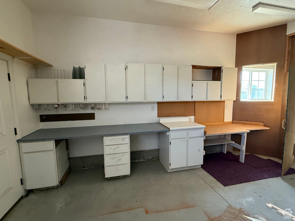 Unfurnished office with concrete floors, built in study area, and a textured ceiling