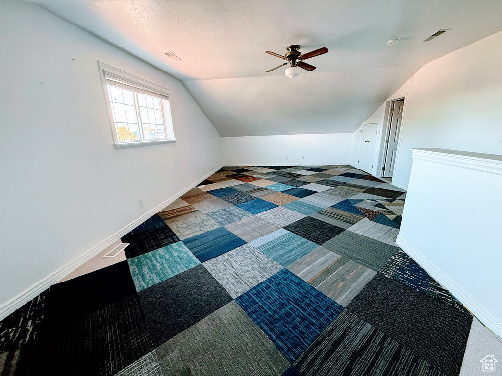Bonus room with vaulted ceiling, ceiling fan, carpet flooring, and baseboards
