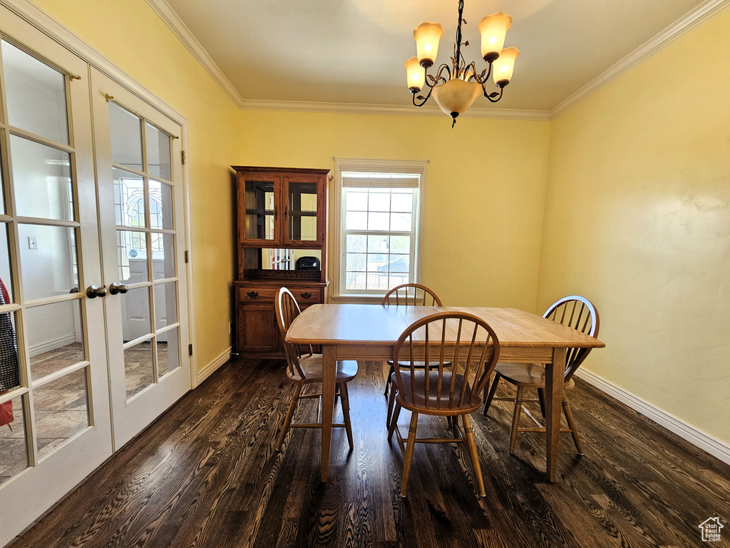 Dining area with crown molding, a chandelier, french doors, baseboards, and dark wood-type flooring