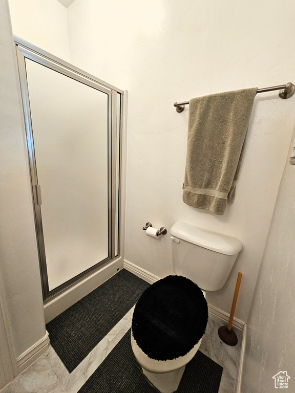 Bathroom with toilet, baseboards, and a stall shower