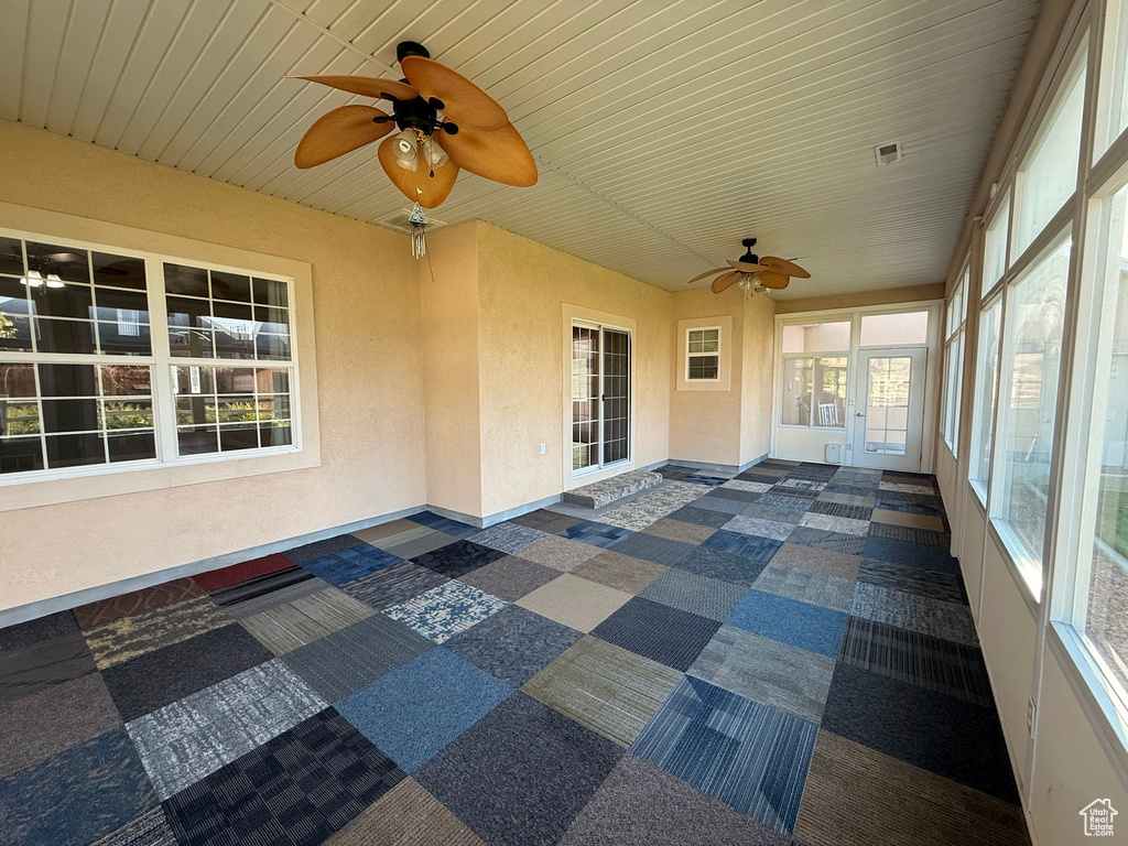 Unfurnished sunroom with ceiling fan, baseboards, and wood ceiling