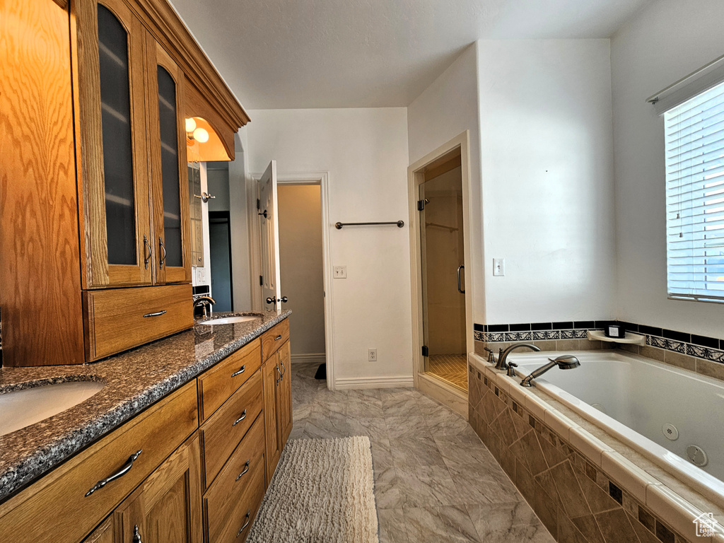 Full bath featuring a jetted tub, a sink, a stall shower, and double vanity