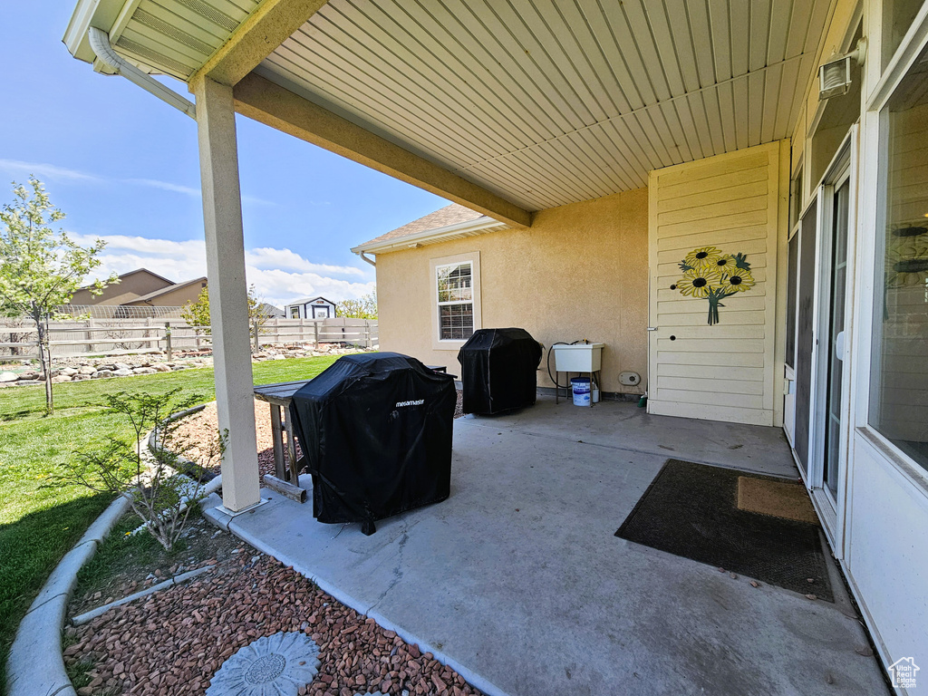 View of patio with fence and a grill