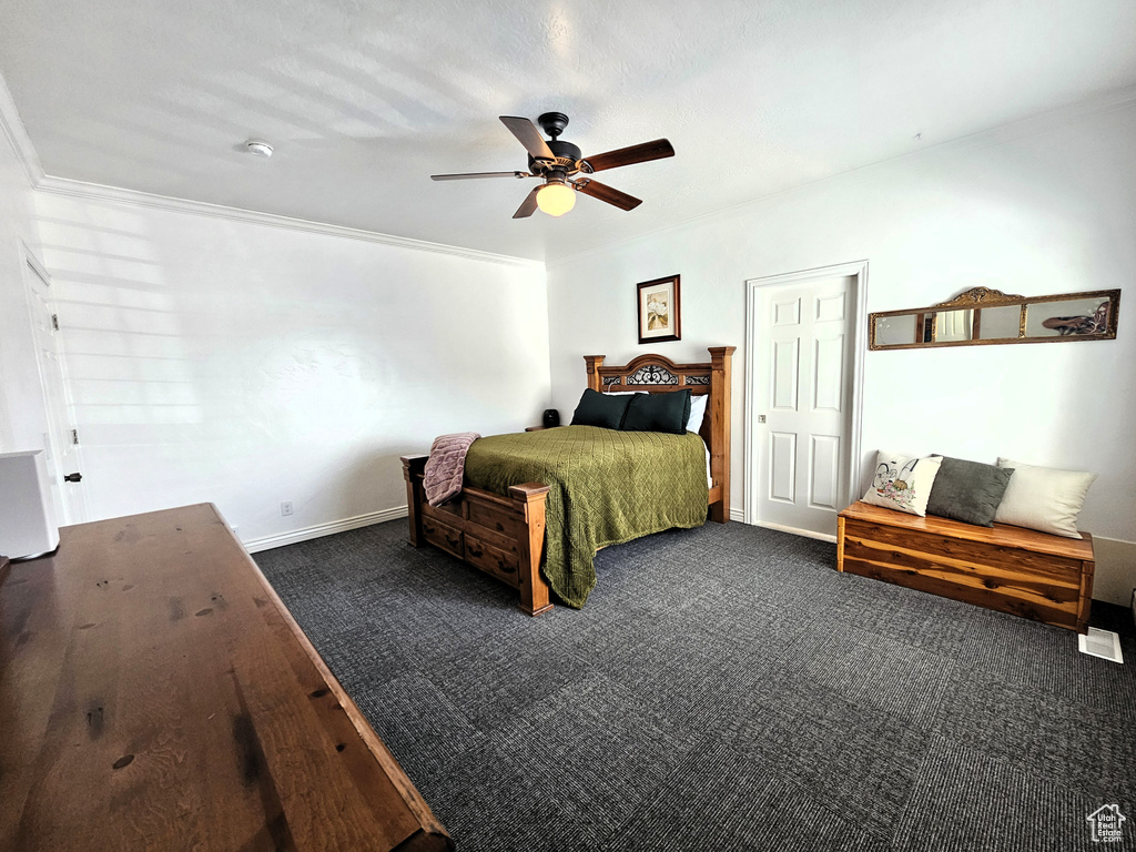 Bedroom with baseboards, ceiling fan, ornamental molding, and dark carpet