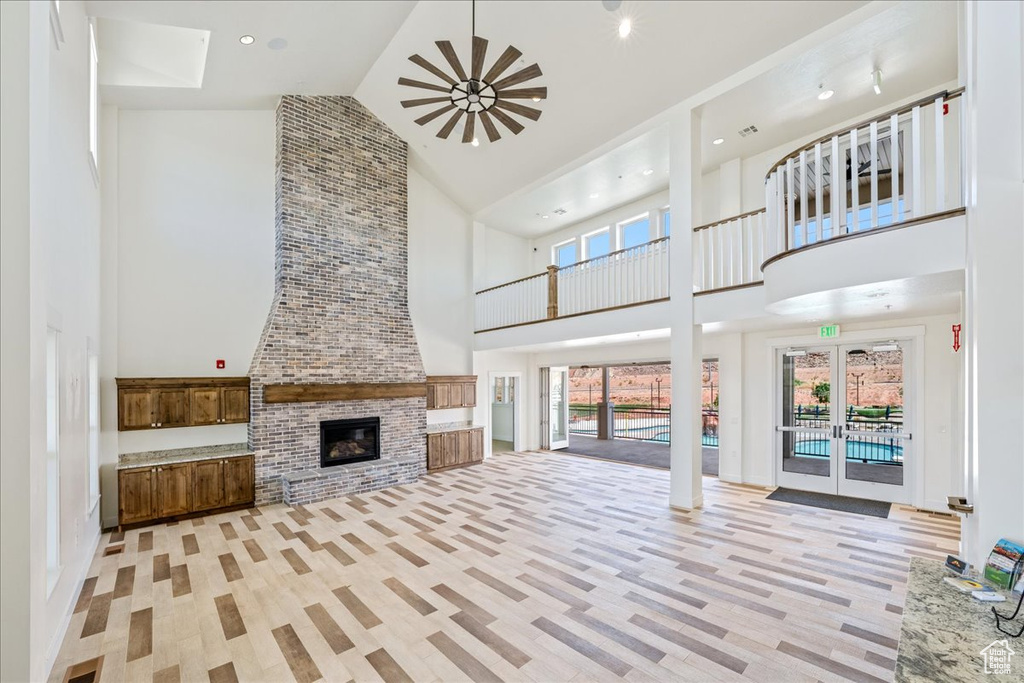 Unfurnished living room featuring high vaulted ceiling, a fireplace, light wood finished floors, and recessed lighting
