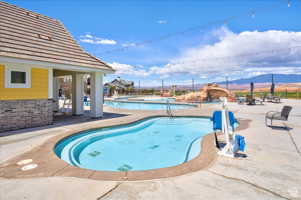 Community pool featuring fence, a mountain view, and a patio area