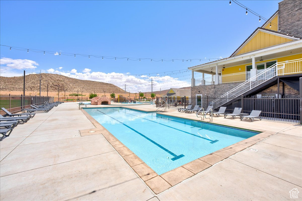 Community pool with stairway, fence, a mountain view, and a patio area