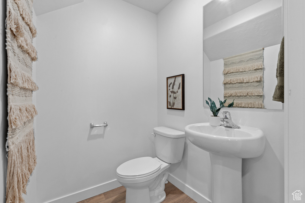 Half bath featuring toilet, baseboards, and wood finished floors