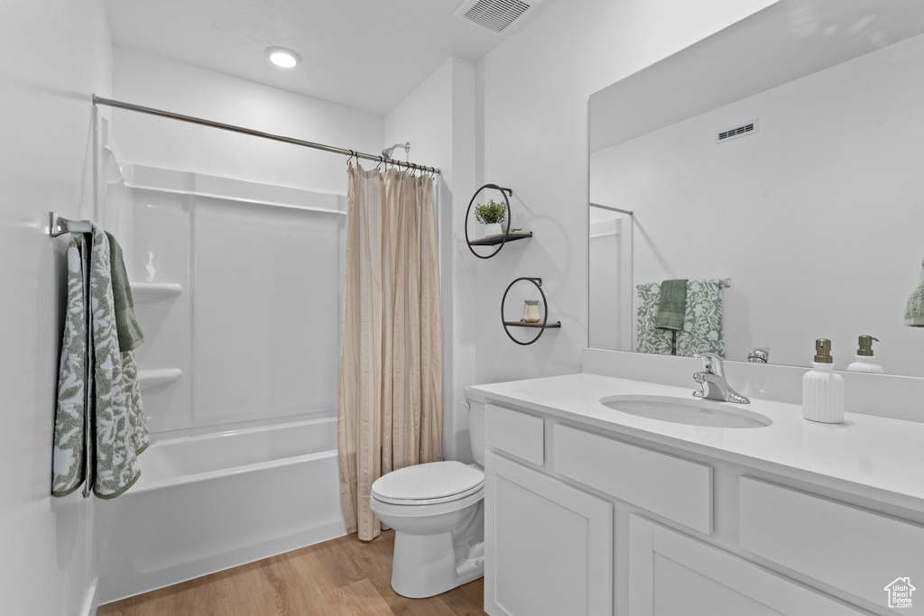 Full bathroom featuring visible vents, wood finished floors, toilet, and shower / bath combo with shower curtain