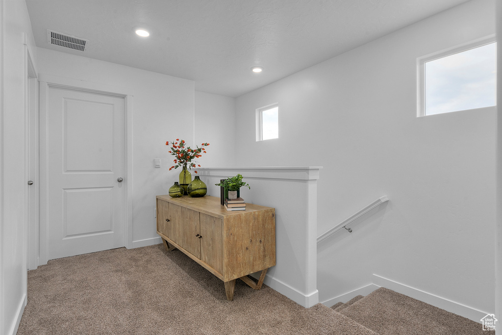Corridor with visible vents, baseboards, recessed lighting, light colored carpet, and an upstairs landing