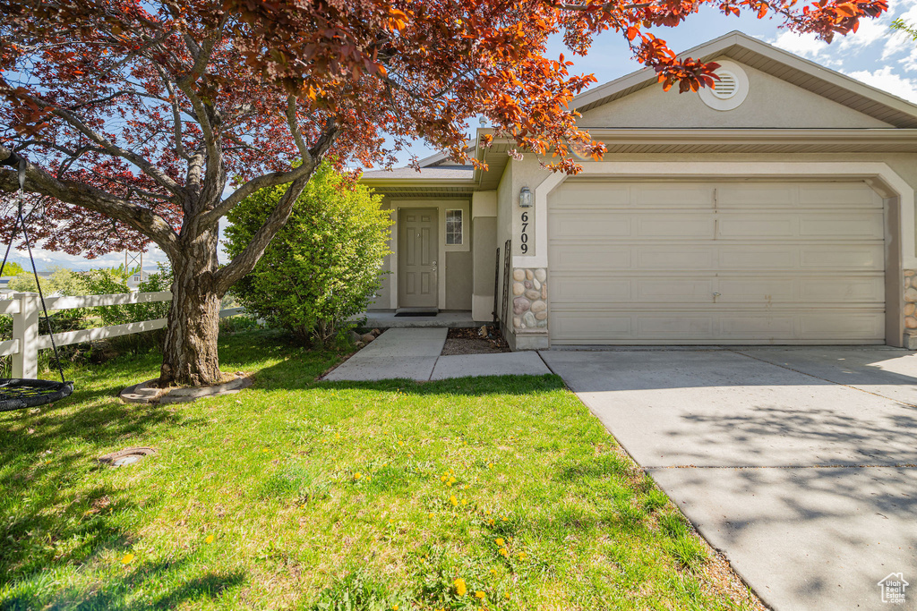 View of front facade with a garage, a front lawn, stucco siding, and concrete driveway