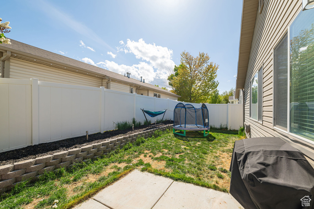 View of yard featuring a patio, a fenced backyard, and a trampoline