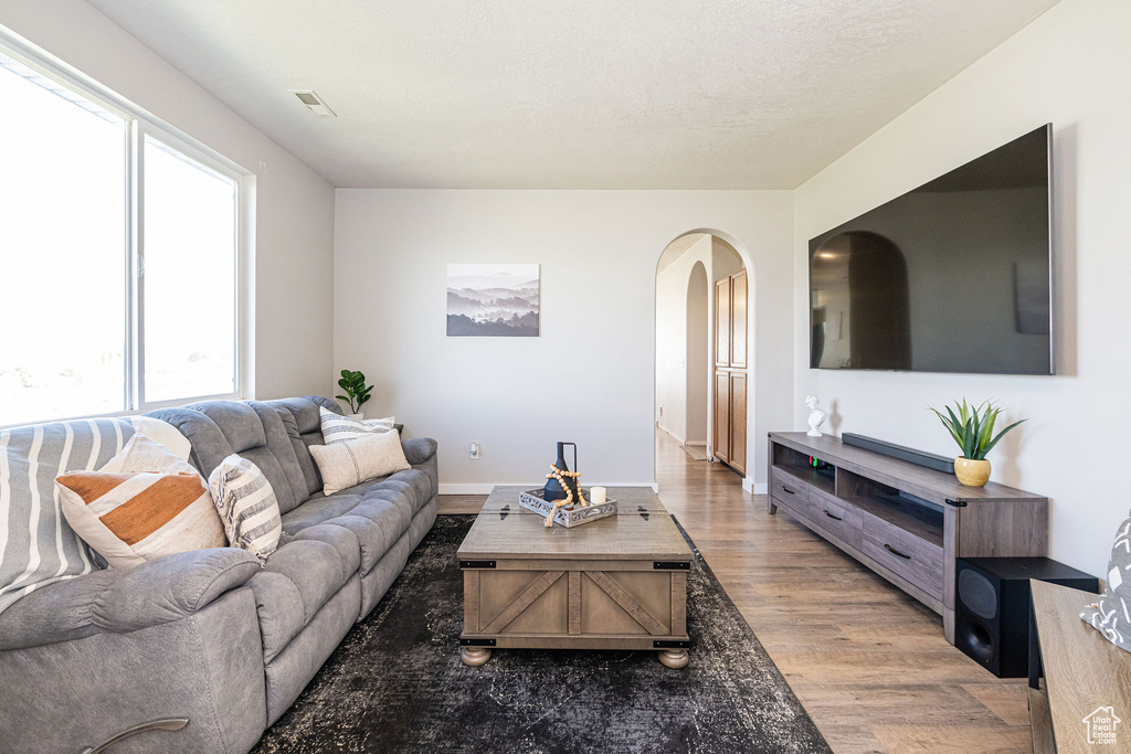 Living room with visible vents, arched walkways, wood finished floors, and a wealth of natural light