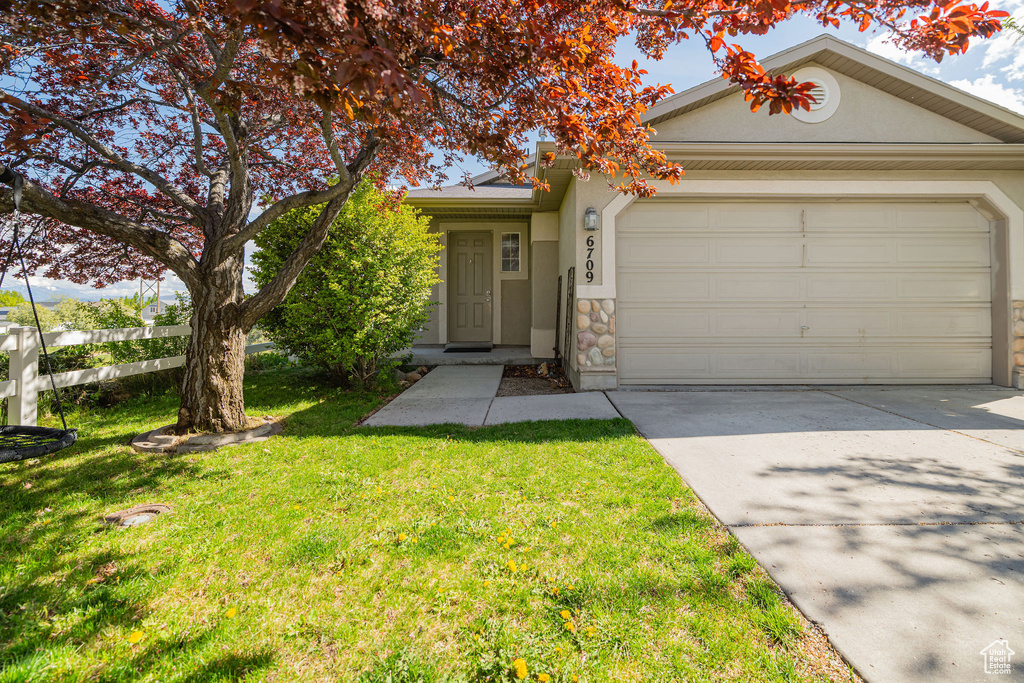 View of front of home with a garage, a front lawn, stucco siding, and concrete driveway