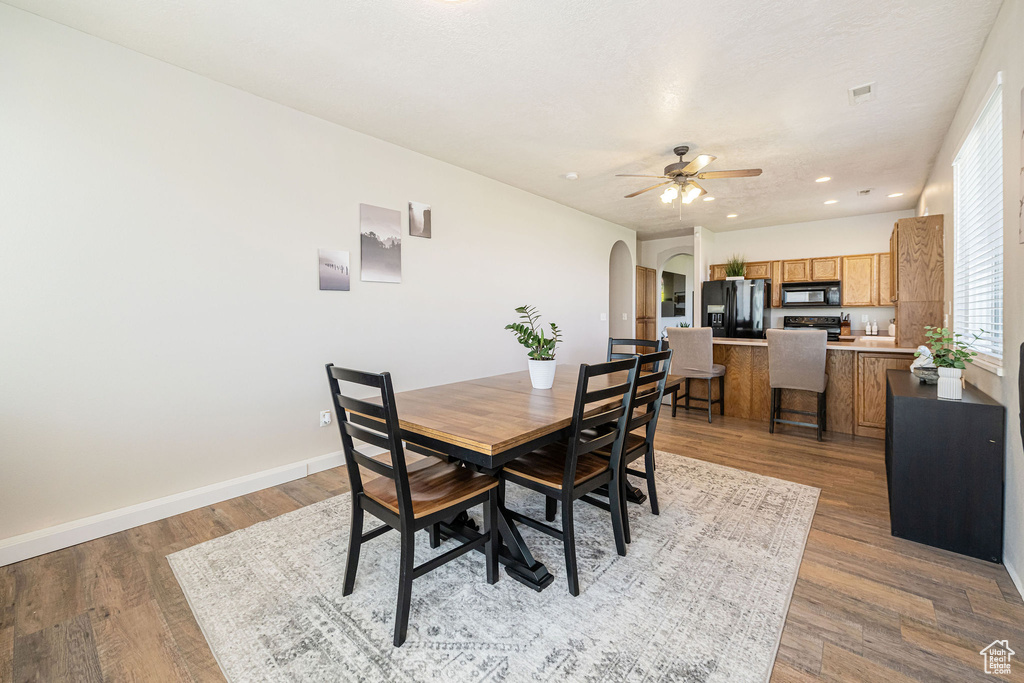 Dining area featuring light wood-style floors, arched walkways, a ceiling fan, recessed lighting, and baseboards