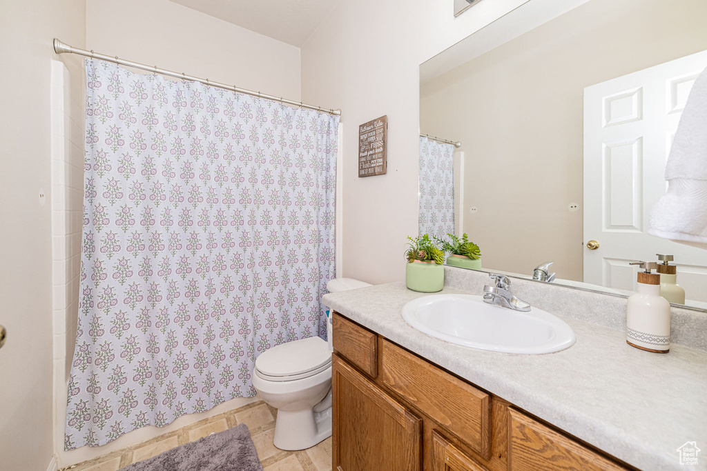 Full bathroom featuring vanity, tile patterned flooring, toilet, and curtained shower