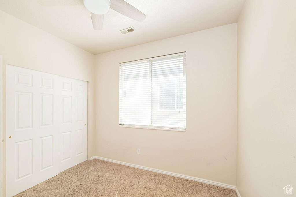 Unfurnished bedroom with visible vents, a ceiling fan, carpet, and baseboards