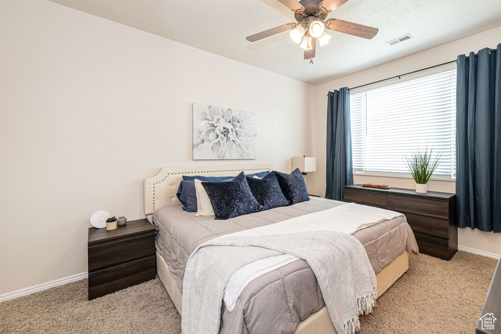Carpeted bedroom featuring visible vents, baseboards, and ceiling fan