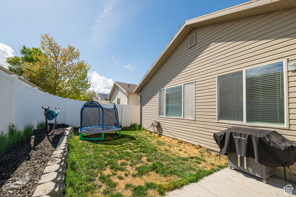 View of yard featuring a patio, a fenced backyard, and a trampoline
