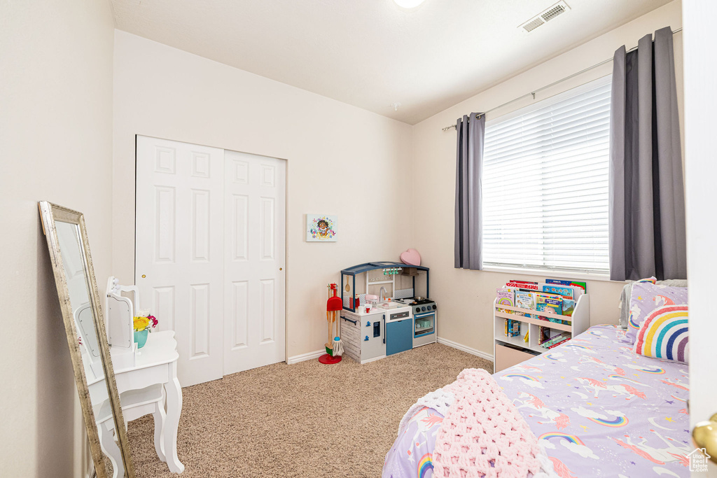 Bedroom featuring carpet flooring, baseboards, visible vents, and a closet