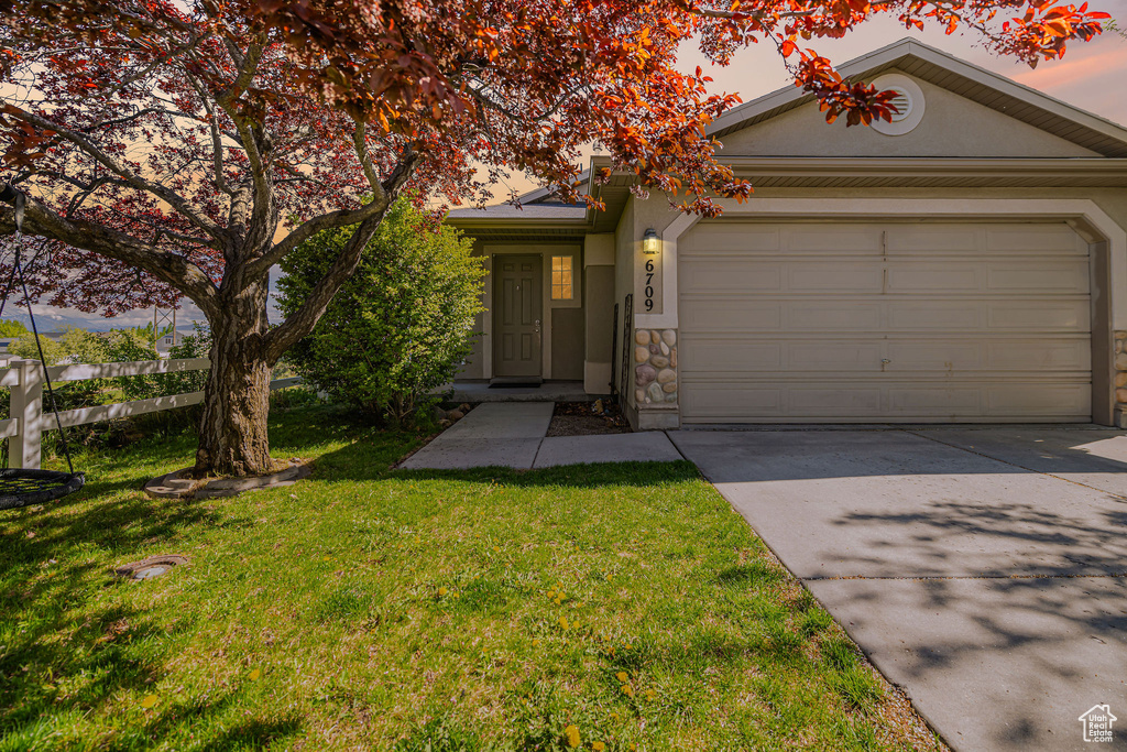 View of front facade featuring an attached garage, stucco siding, concrete driveway, and a front lawn
