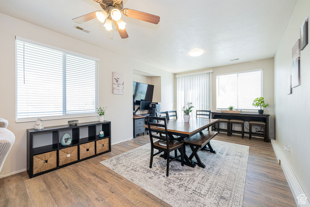 Dining area featuring ceiling fan, baseboards, visible vents, and wood finished floors