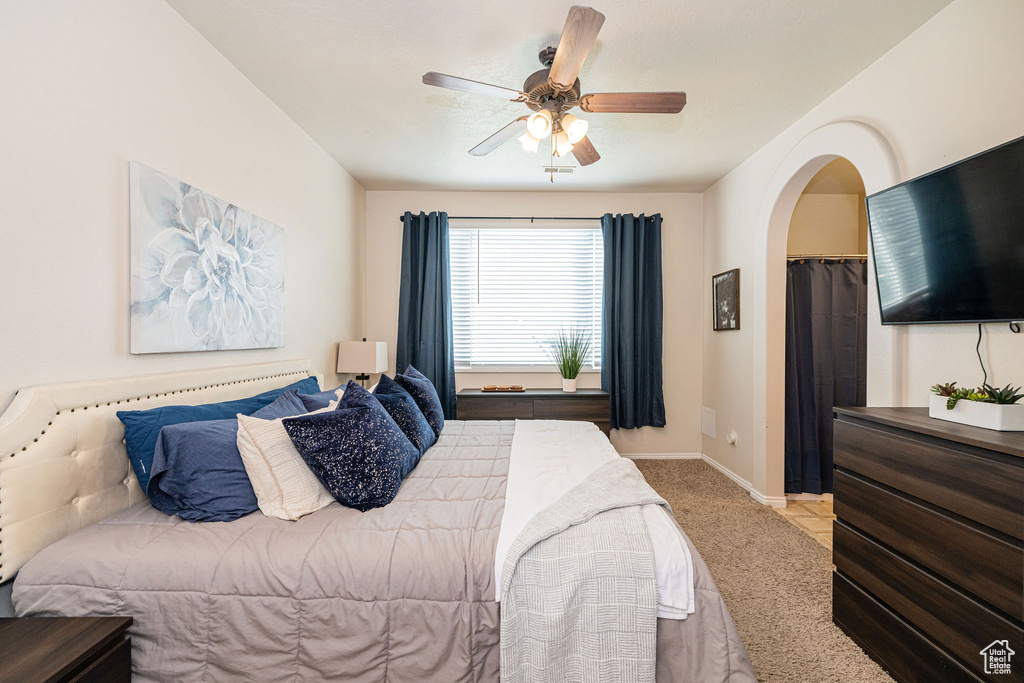 Carpeted bedroom featuring baseboards, arched walkways, and a ceiling fan