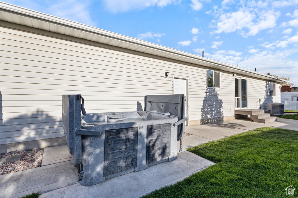 Rear view of property with a yard, exterior kitchen, an outdoor bar, and central air condition unit