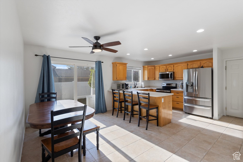 Kitchen with a breakfast bar, ceiling fan, recessed lighting, light countertops, and appliances with stainless steel finishes