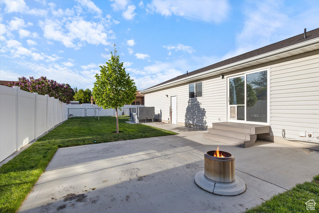 Rear view of property with a lawn, fence, a patio, and an outdoor fire pit